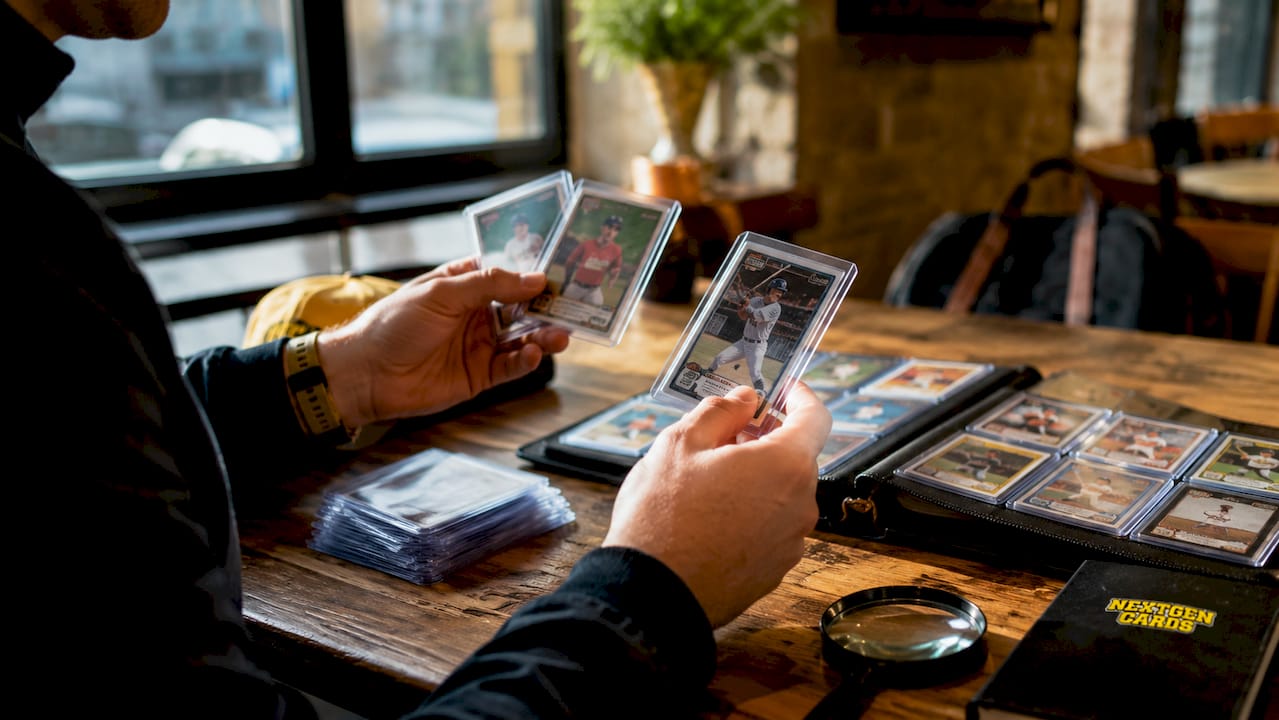 Hands sorting sports card inserts on wooden desk
